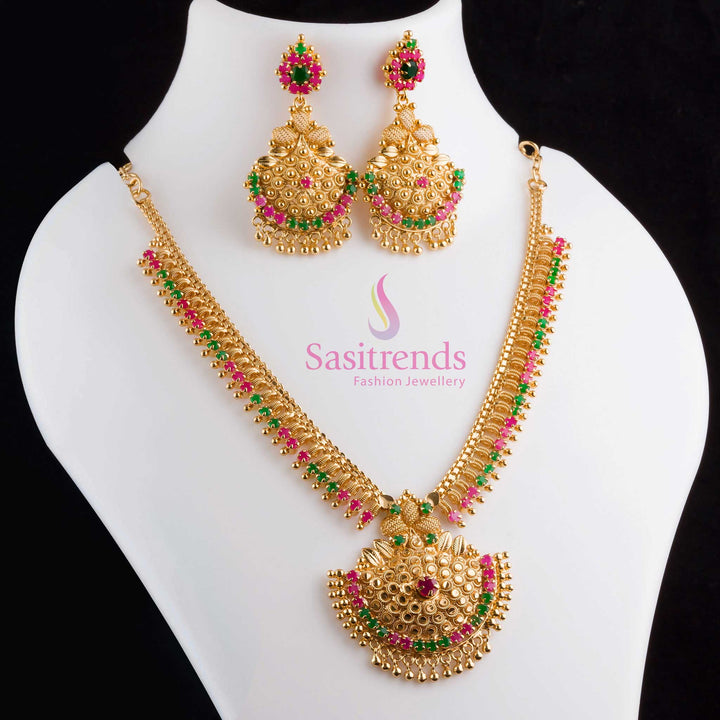 Elegant Tilak motif ruby-green necklace and earrings set in micro gold plating with sparkling AD crystals, crafted for a vibrant ceremonial jewellery look – Sasitrends