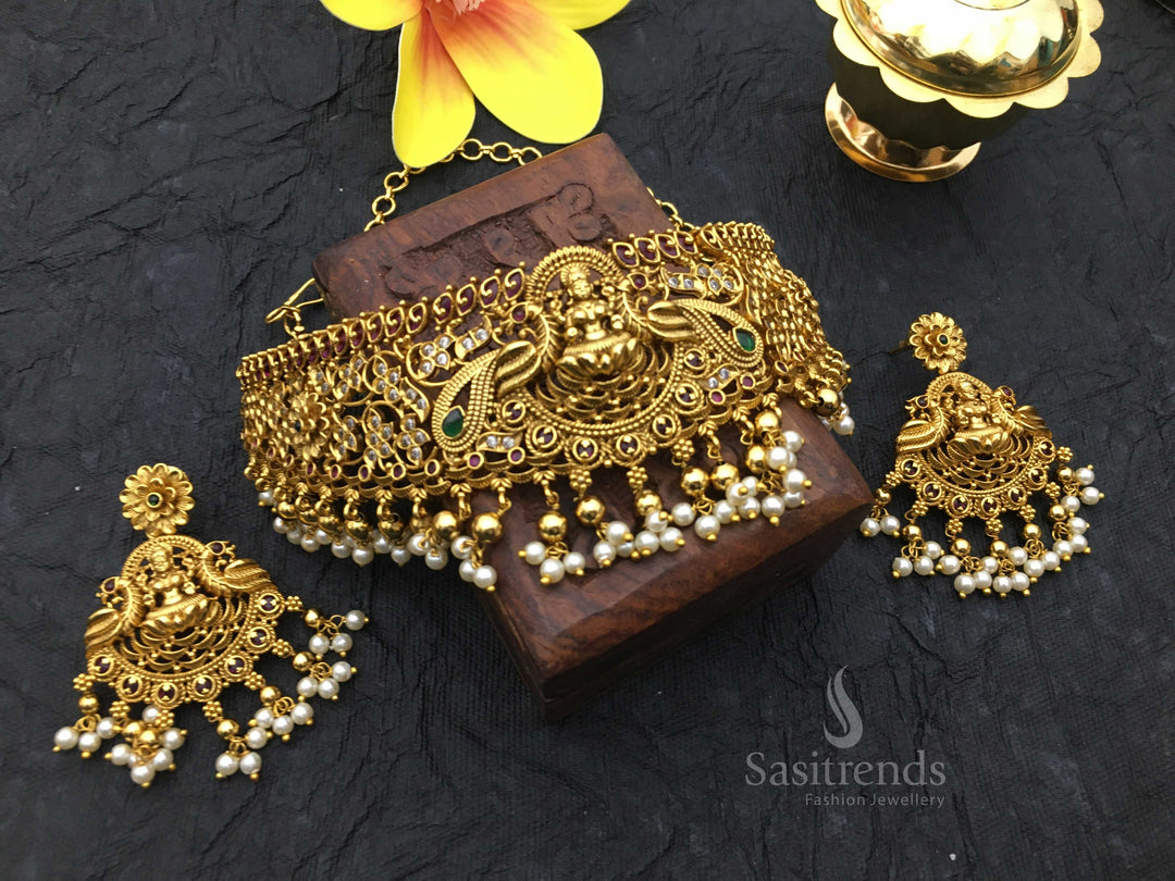 Stunning temple matte gold plated choker jewellery set featuring elegant Lakshmi and peacock motifs with sparkling AD stone embellishments, curated for a regal bridal look and traditional ceremony glamour – sasitrends