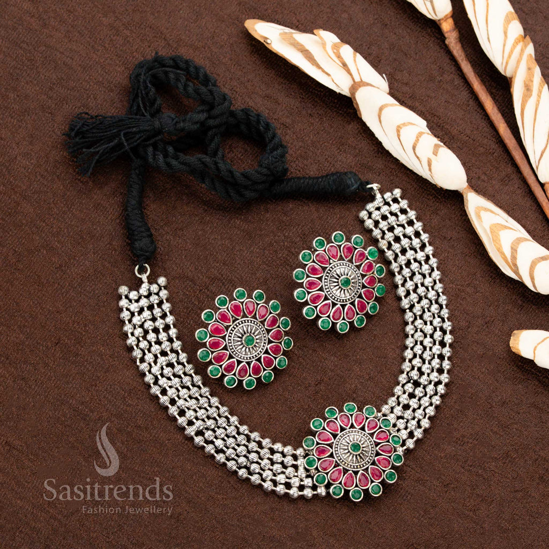 Antique oxidised German silver choker set featuring an intricately designed floral pendant with ruby and green gemstones, making it a stunning jewellery piece for ethnic fashion and festive celebrations - Sasitrends
