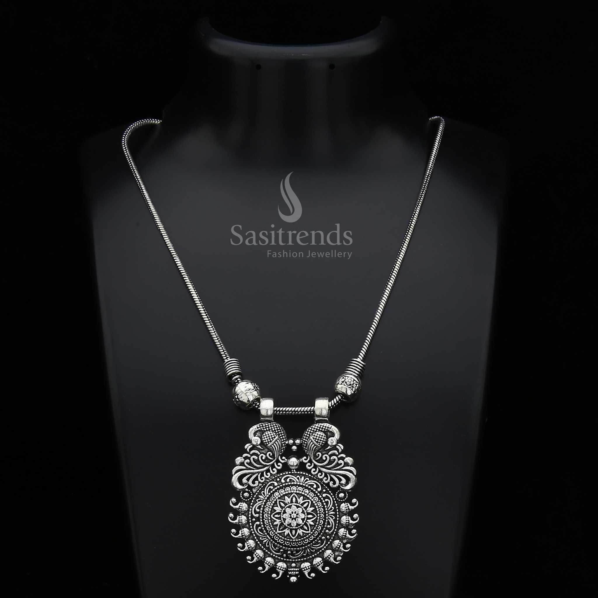 Enchanting Mayurika necklace featuring an oxidised silver and antique gold fusion pendant with majestic peacock, floral carvings, and mango motifs – a vibrant traditional jewellery treasure ideal for ethnic and festive occasions – Sasitrends