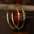 Gold-plated kada bangles with red and green enamelled bead accents