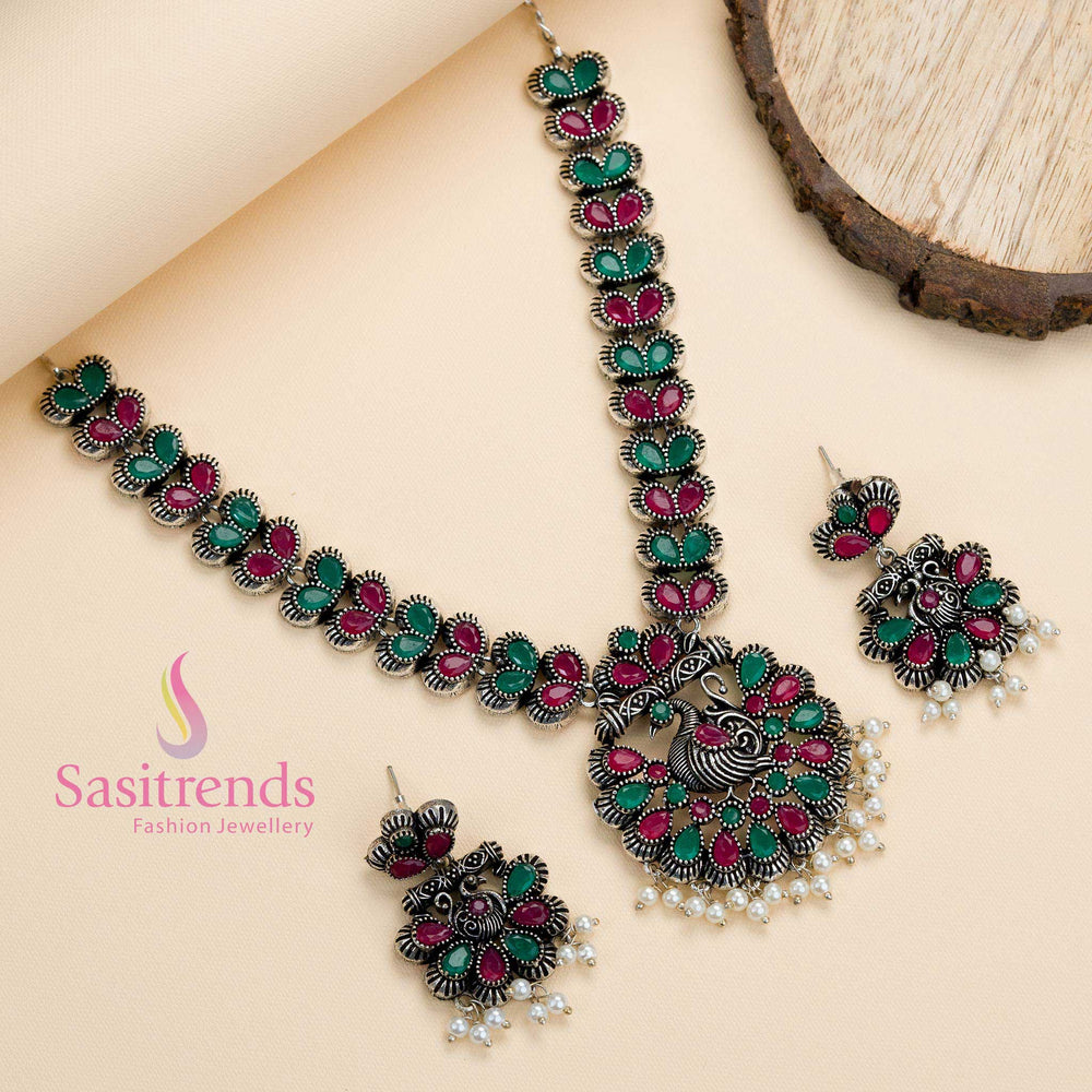 Oxidised peacock pendant jewellery set in ruby-green stones with delicate pearl drops, blending heritage detailing with festive fusion elegance – Sasitrends