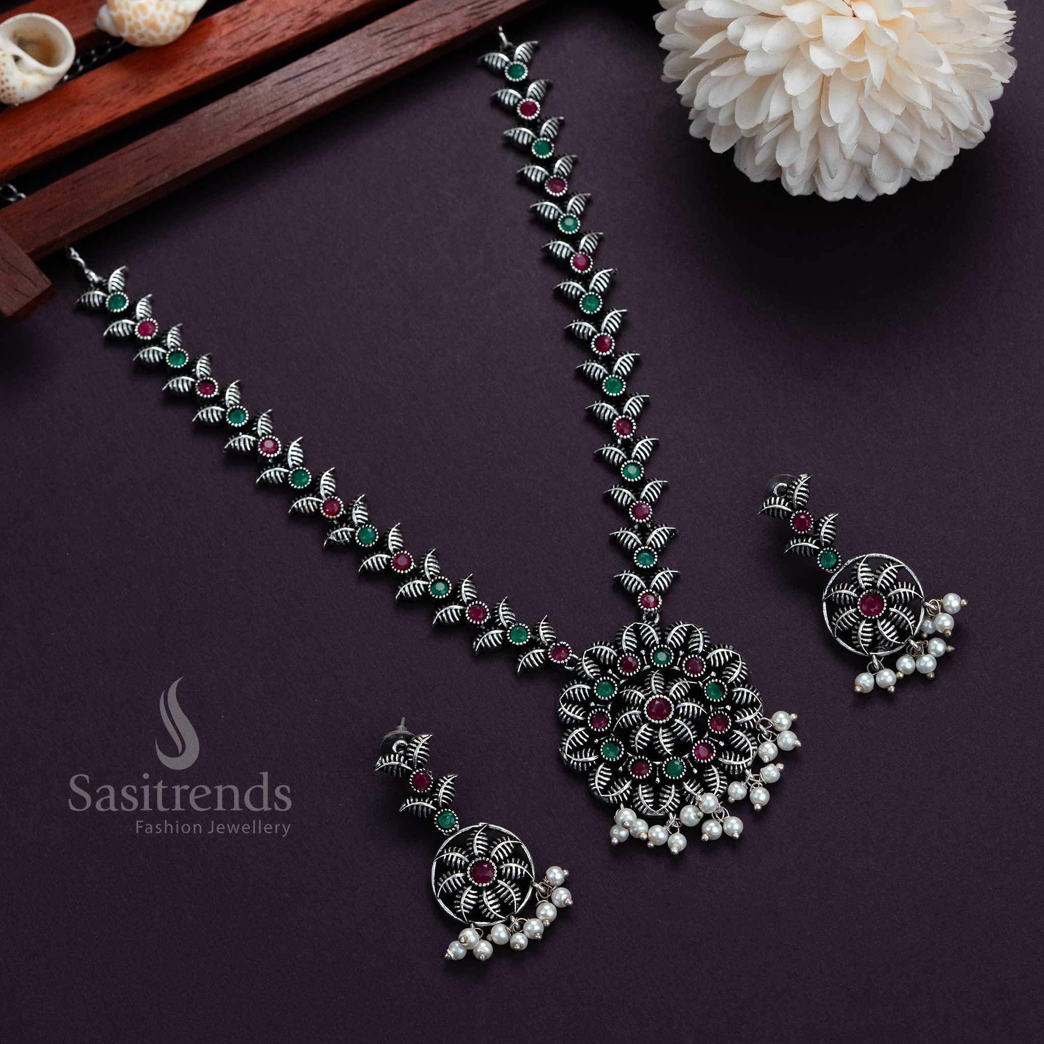 Fusion-style oxidised silver necklace in ruby-green stones with floral-leaf pendant and pearl earrings, a celebration-ready festive jewellery set – Sasitrends