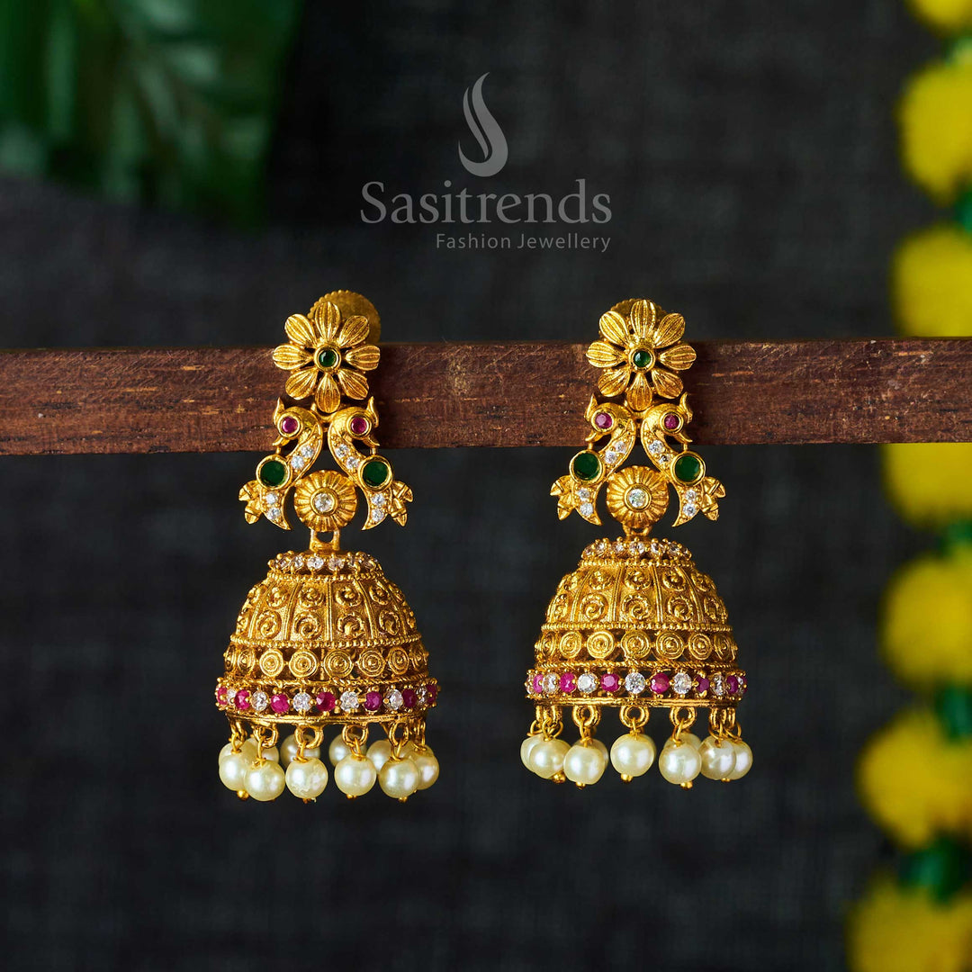 Floral and peacock temple jhumkas in matte gold with multi-hue brilliance, enhanced with AD sparkle and pearl embellishments for celebration-ready traditional elegance by Sasitrends
