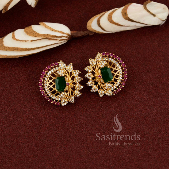 Ornate temple matte gold floral earrings with a centre green AD stone and intricate leaf pattern, crafted for a refined cultural jewellery look - Sasitrends
