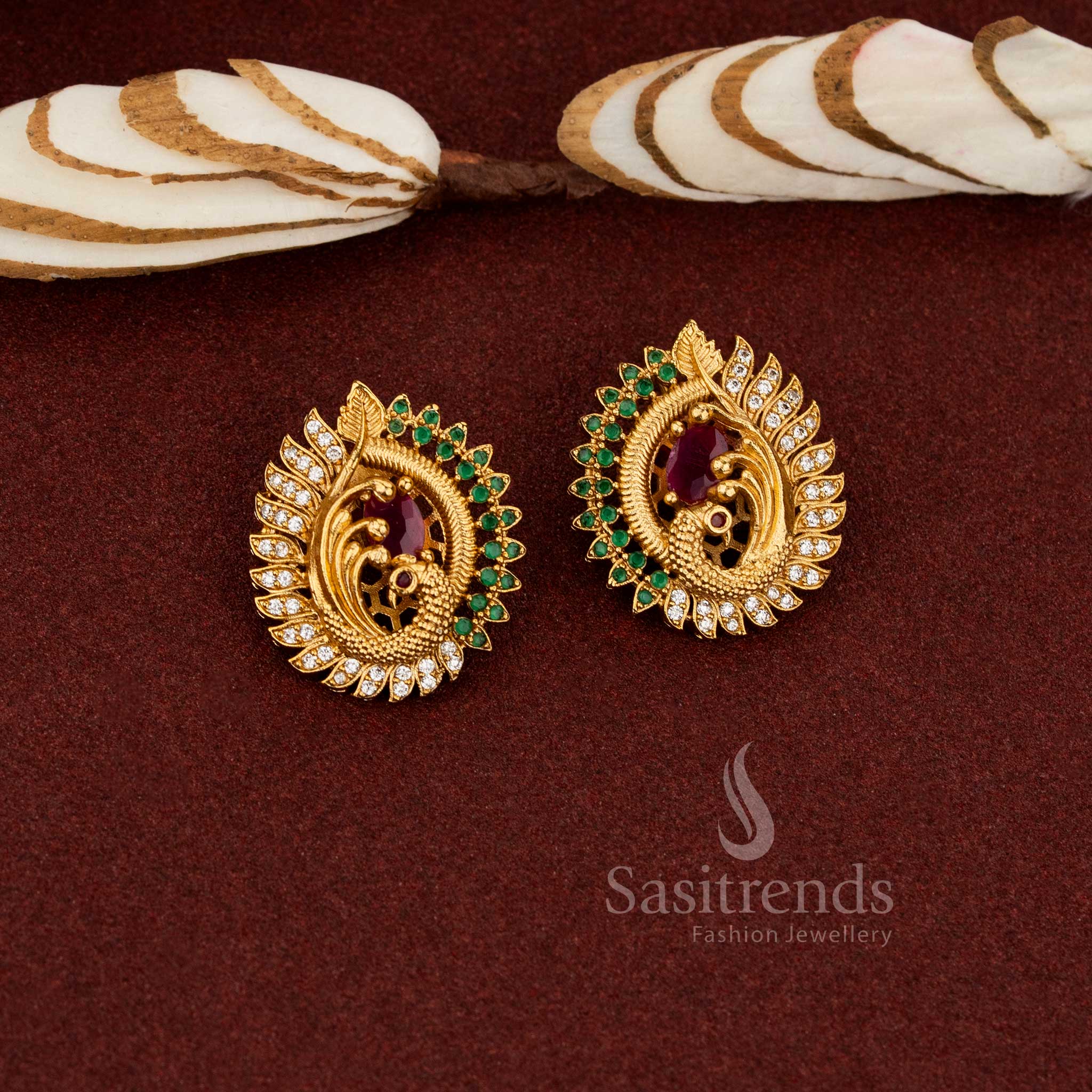 Ornate peacock face temple earrings with a centre ruby AD stone in a matte gold tone, perfect for enhancing ethnic jewellery collections - Sasitrends