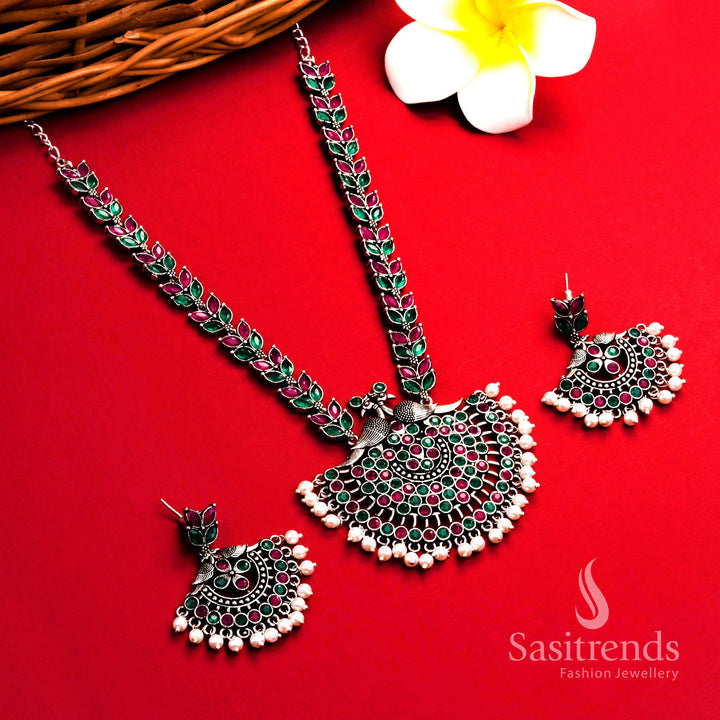 Vibrant ruby-green oxidised silver pearl long necklace featuring peacock floral pendant and matching pearl earrings – ethnic festive jewellery – Sasitrends