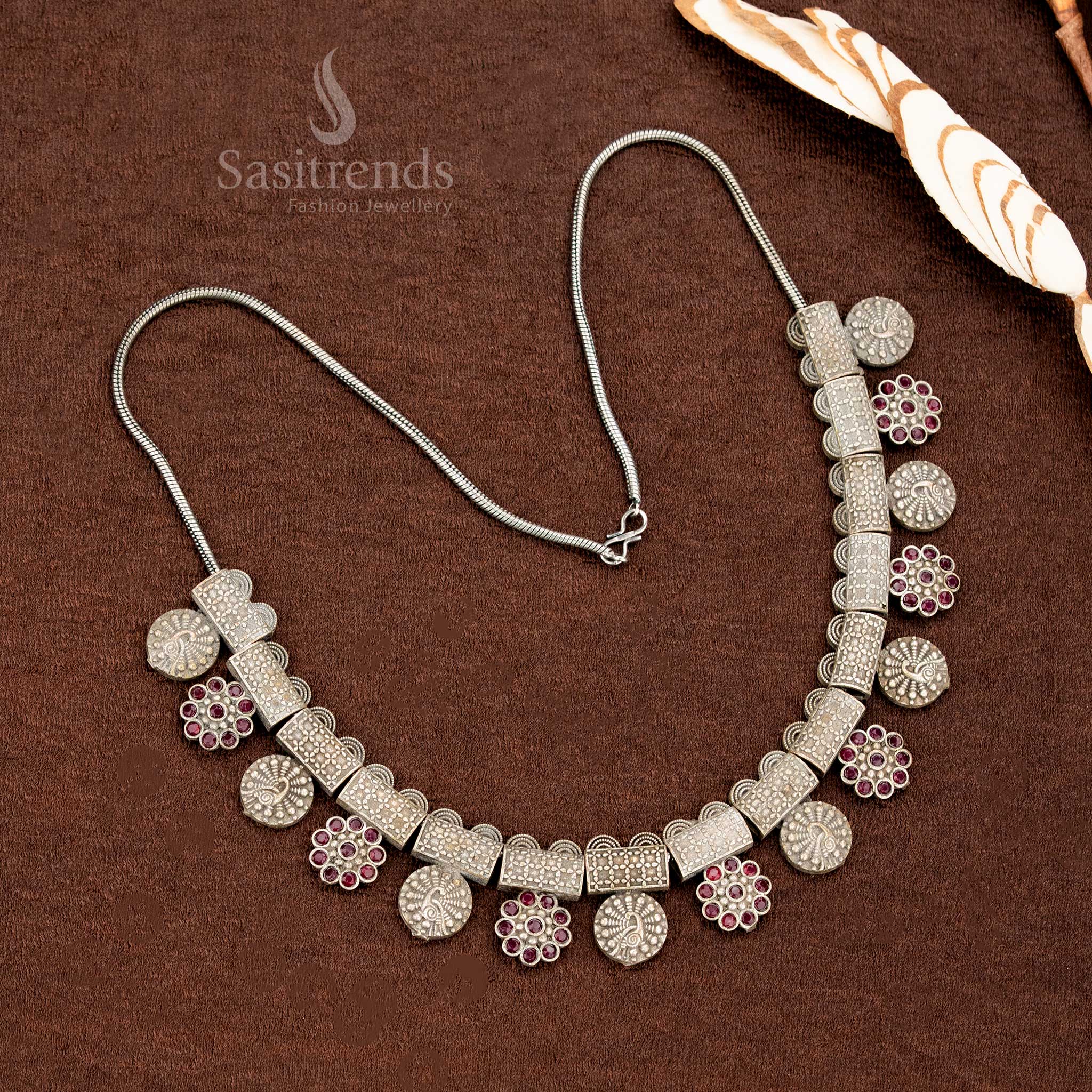 Traditional ruby necklace set in oxidised German silver adorned with floral hanging accents, bold block patterns, and elegant coin studs – a heritage-inspired saree jewellery set by Sasitrends