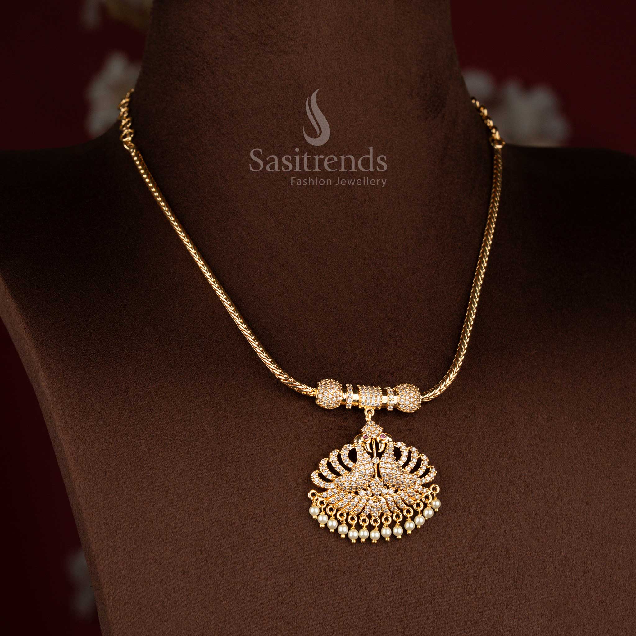 Sasitrends micro gold plated one gram pendant chain necklace featuring a dual peacock pendant structure with arched feather detailing, set in white AD stones and finished with pearl drops, ideal for temple visits, festive functions, and pairing with traditional silk sarees.