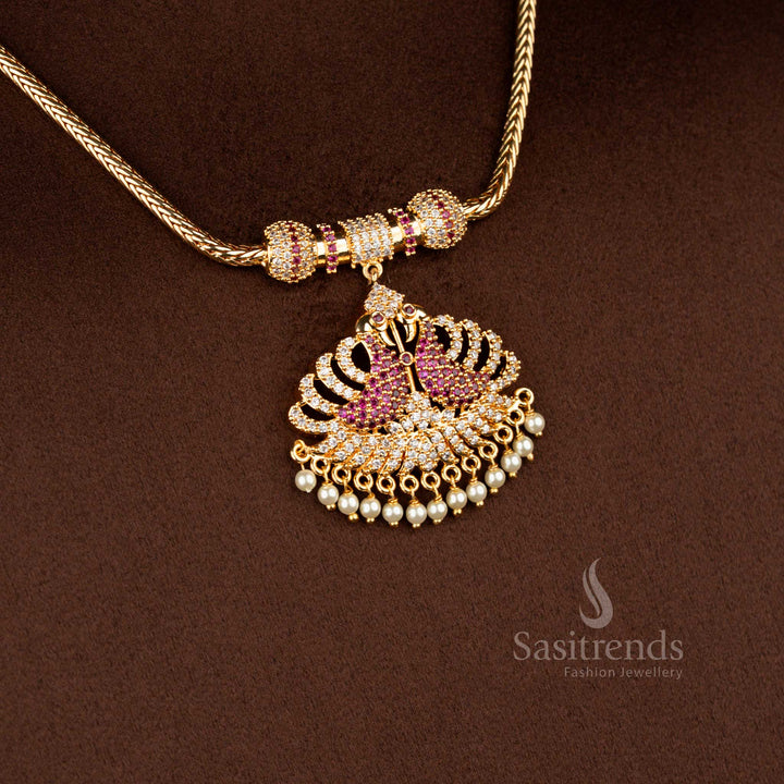 Sasitrends micro gold plated one gram pendant chain necklace crafted with a dual peacock pendant structure accented by white AD stones and white ruby highlights, finished with pearl drops and ideal for temple wear and festive occasions.