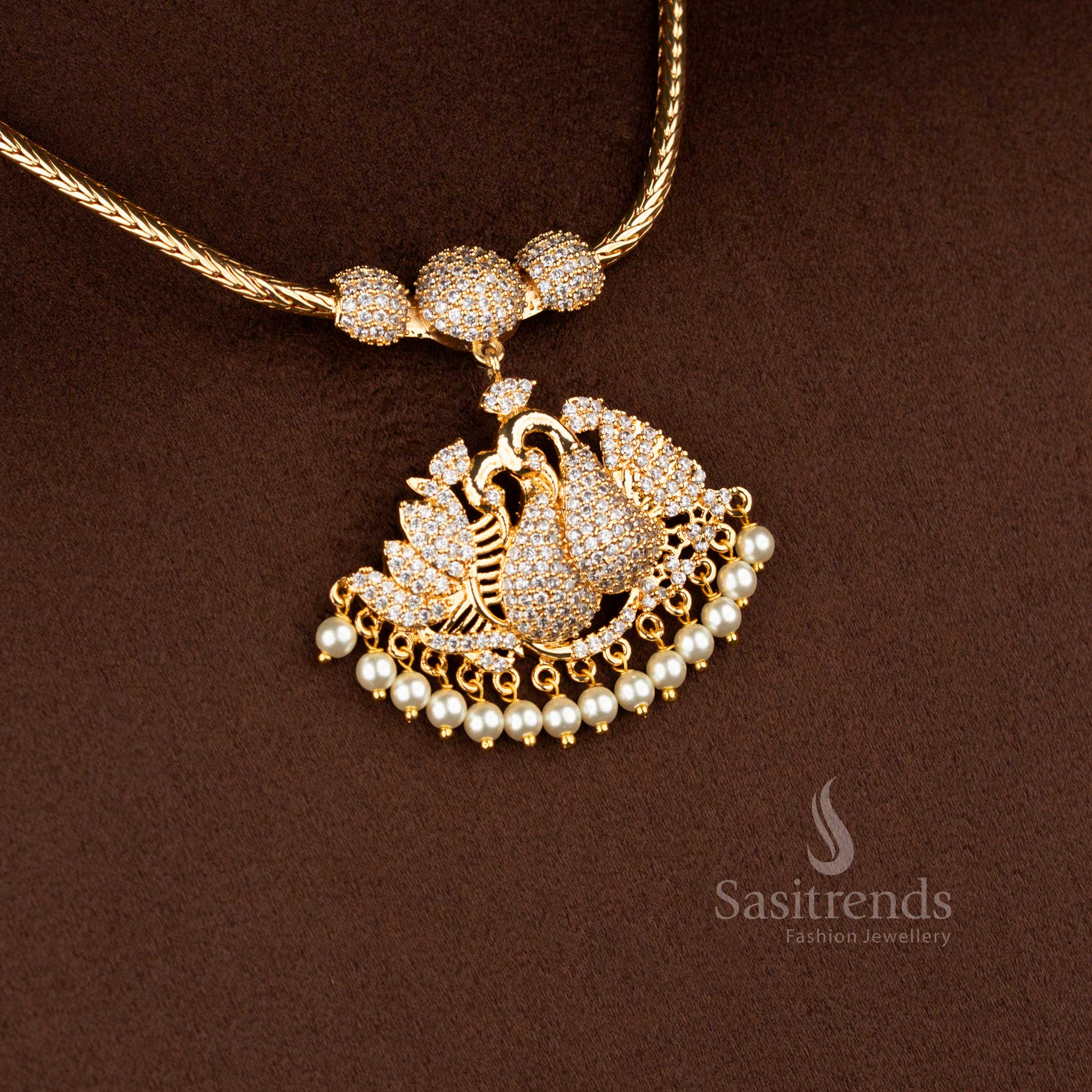 Sasitrends micro gold plated one gram pendant chain necklace featuring a single peacock pendant structure with paisley-style feather detailing, set in white AD stones and finished with pearl drops, ideal for temple wear, poojas, and traditional silk sarees.