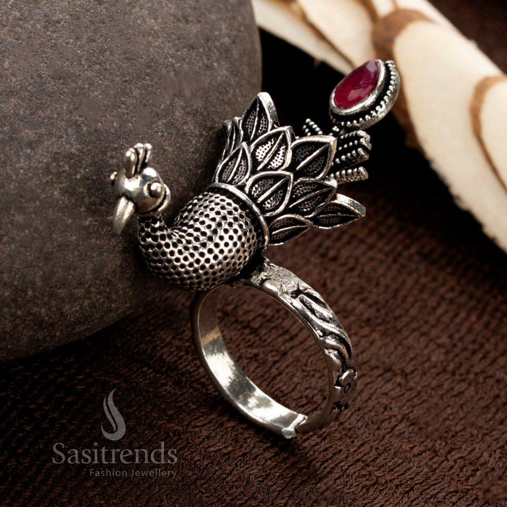 A traditional handcrafted oxidised silver peacock ring with finely engraved feathers, adorned with a striking ruby stone, a perfect blend of grace and timeless artistry - Sasitrends