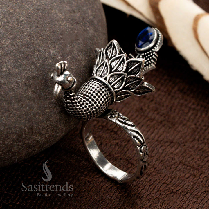 A vintage oxidised silver peacock ring with exquisitely engraved plume details, featuring a striking sapphire blue stone, a captivating piece of ethnic statement jewellery - Sasitrends