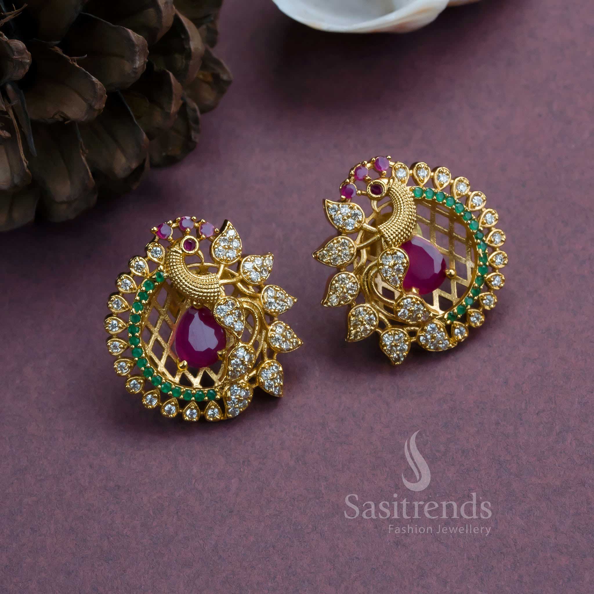 Temple jewellery-style peacock earrings with matte gold plating and AD studs, crafted with feathered flair, elegant drape, and royal grandeur for festive occasions by Sasitrends