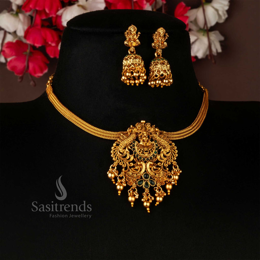 Divine temple matte gold choker jewellery set designed with serene green AD stones, highlighting a sacred Lakshmi and peacock pendant motif, complemented by traditional jhumkas – a graceful accessory for spiritual and festive occasions – Sasitrends