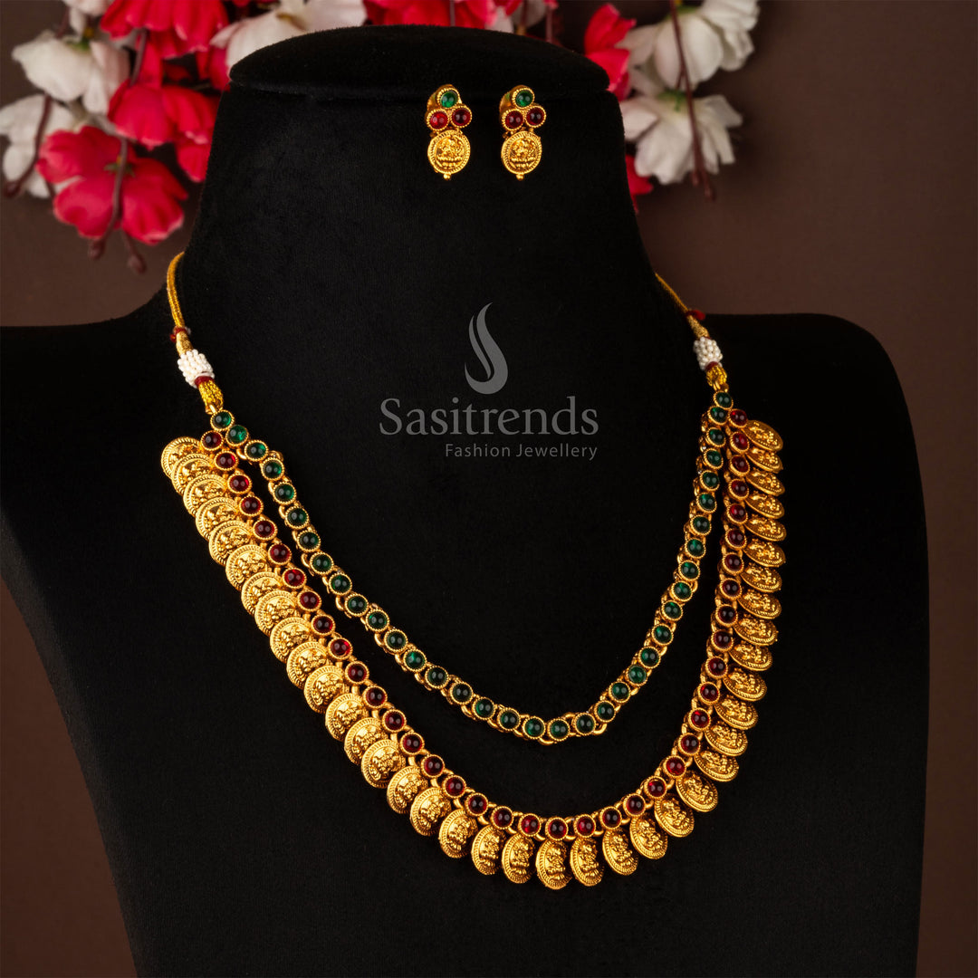 Elegant two-layer Lakshmi coin necklace with ruby-green stones in a matte gold base, paired with matching ethnic earrings – timeless jewellery – sasitrends