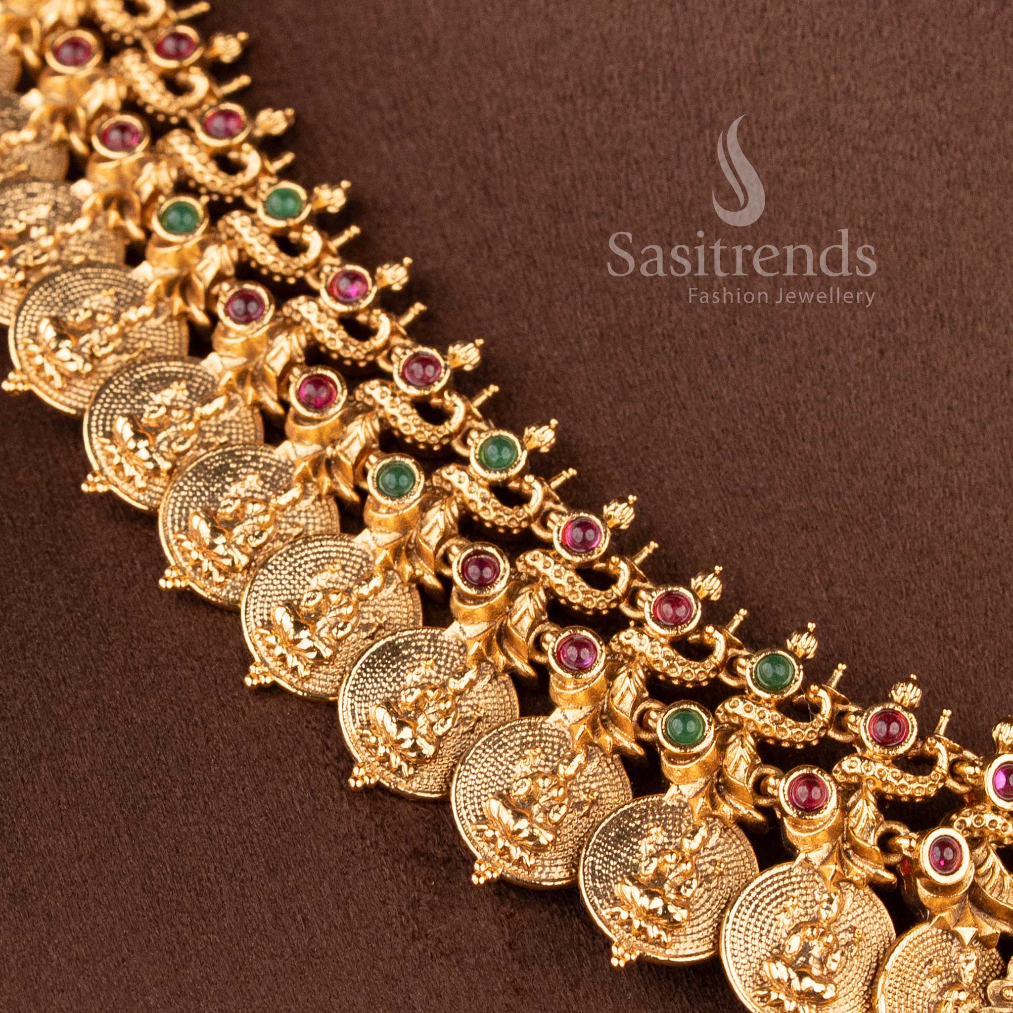 Elegant South Indian bridal temple jewellery set featuring Lakshmi peacock haram necklace in matte gold finish with ruby green stones and matching jhumkas by Sasitrends