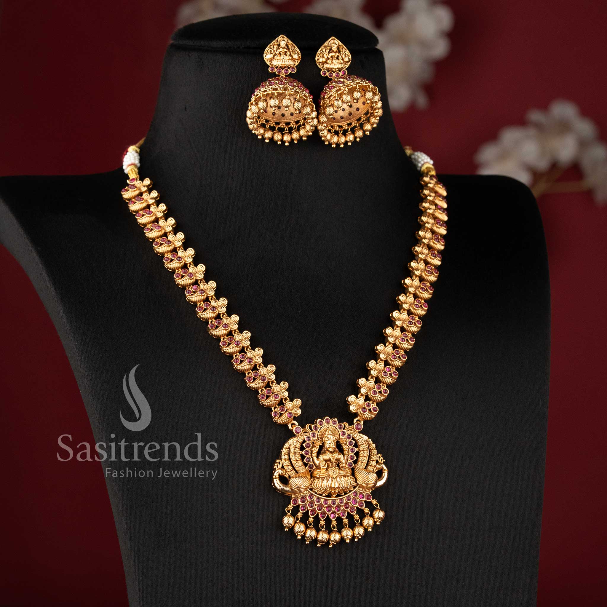 Traditional Nakshi style temple jewellery set with Lakshmi peacock haram necklace in ruby color and matching jhumkas in matte gold tone by Sasitrends