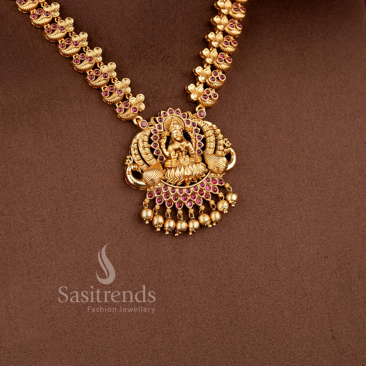 Traditional bridal wear temple matte gold tone Lakshmi and peacock haram necklace jewellery set in ruby green color with matching jhumkas by Sasitrends, perfect for wedding and festive occasions