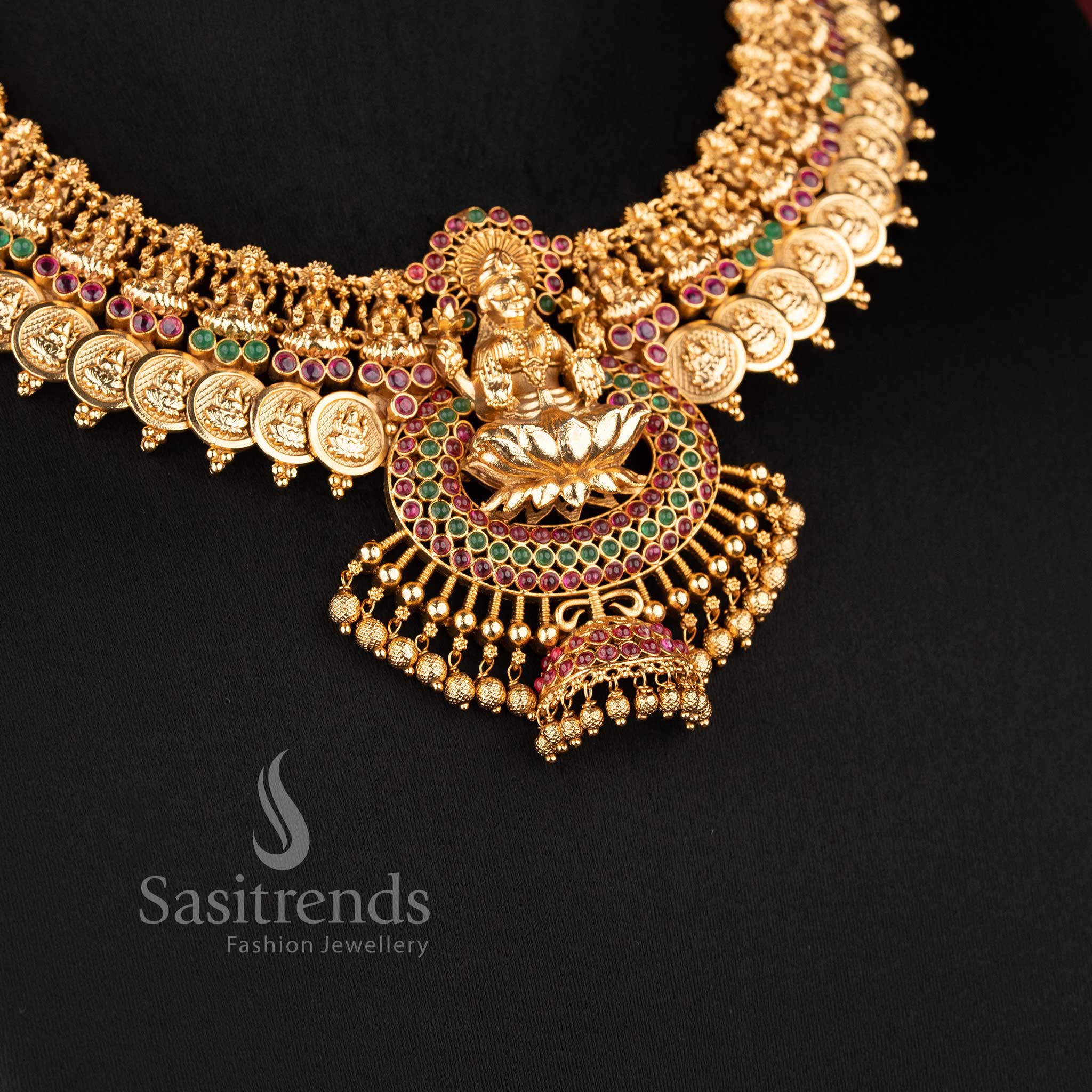 Traditional temple jewellery necklace set with Lakshmi lotus and kasu design in ruby green color and matte gold tone by Sasitrends for bridal wear