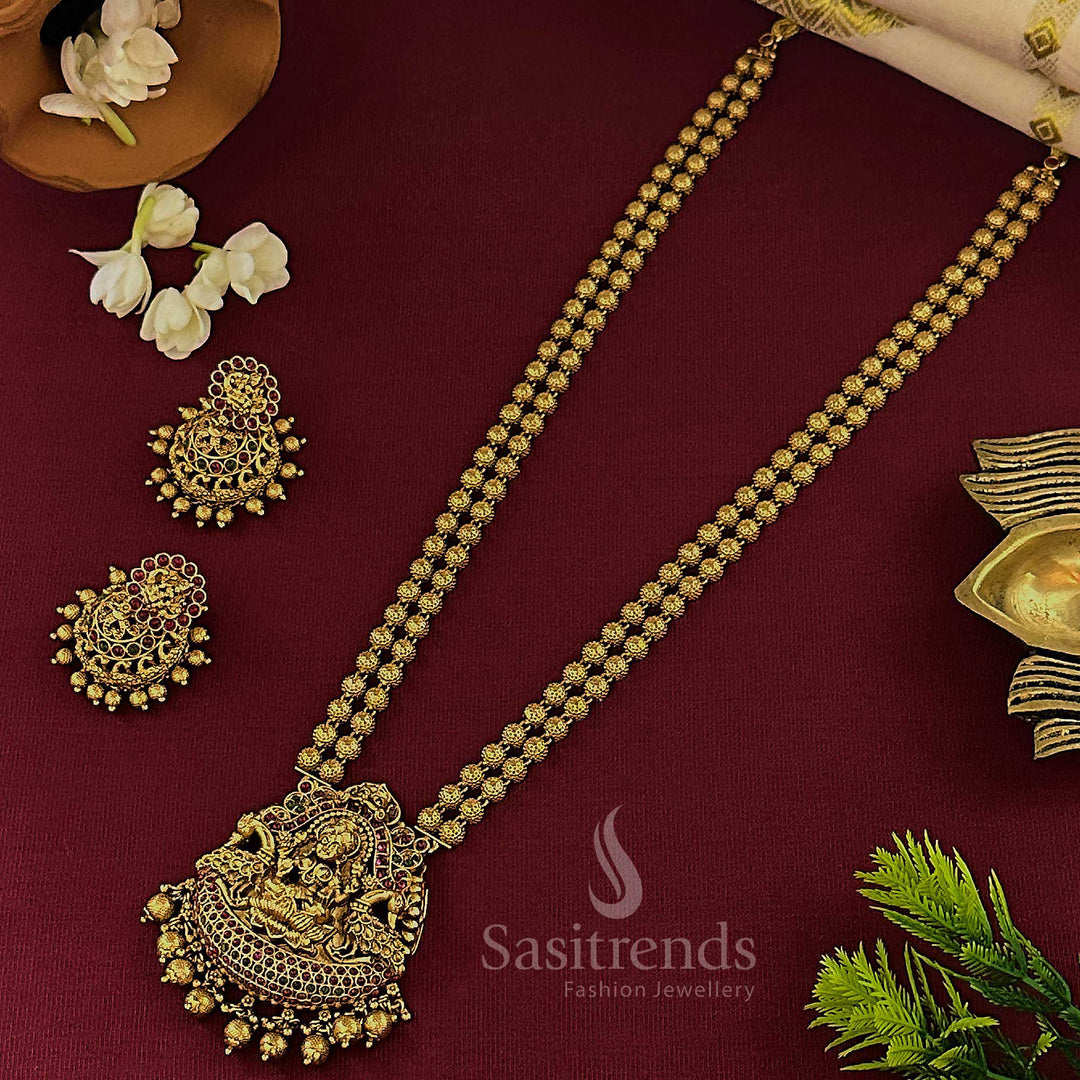 Traditional matte gold double layer long temple jewellery set with Lakshmi motif pendant, vibrant ruby-green bead combination and statement jhumkas, perfect for an authentic bridal ensemble – sasitrends

