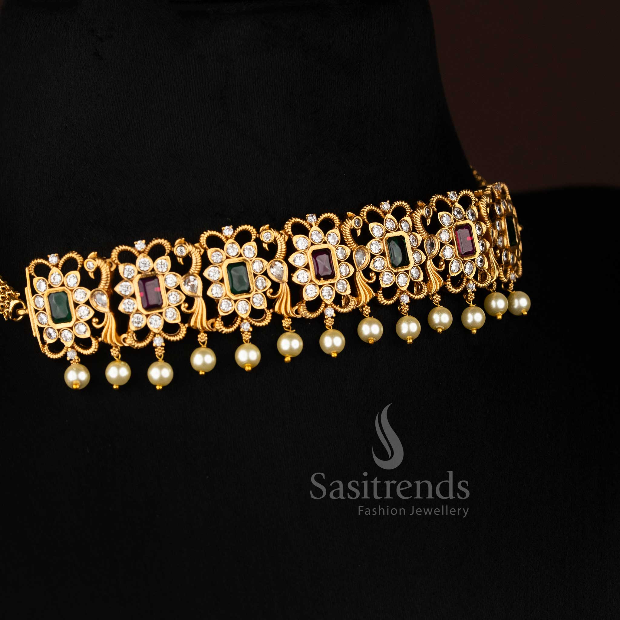 Matte gold plated peacock choker necklace, showcasing an elegant combination of deep ruby and brilliant emerald green stones with AD accents and dangling pearls, ideal for festive occasions from Sasitrends