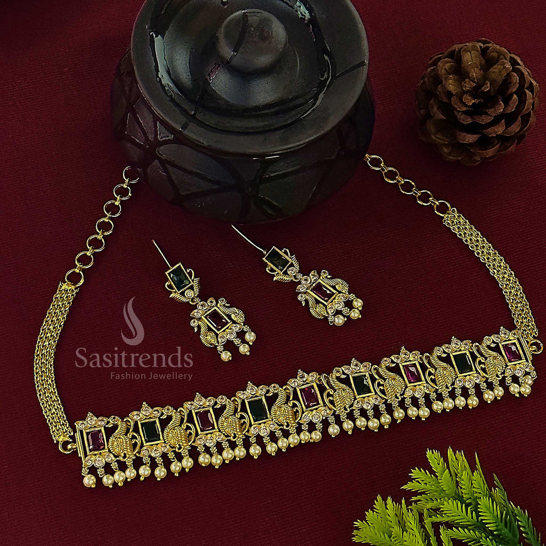 Ornate traditional matte gold plated peacock choker necklace, showcasing an elegant combination of deep ruby and brilliant emerald green stones with AD accents and dangling pearls, ideal for festive occasions from Sasitrends
