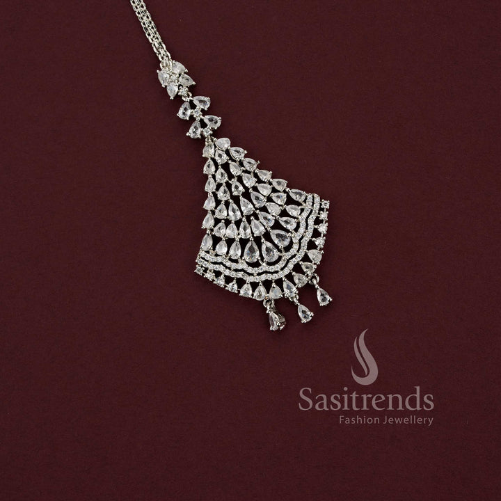Elegant engagement silver AD stone maang tikka with a sophisticated triangular fan motif and dangling teardrop charms, ideal for styling with silk sarees and festive wear