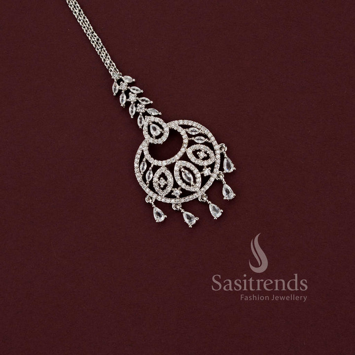 Elegant party wear silver AD stone maang tikka 2129E with a unique basket-shaped filigree motif and dangling teardrop charms, an ideal accessory for sarees and festive outfits.