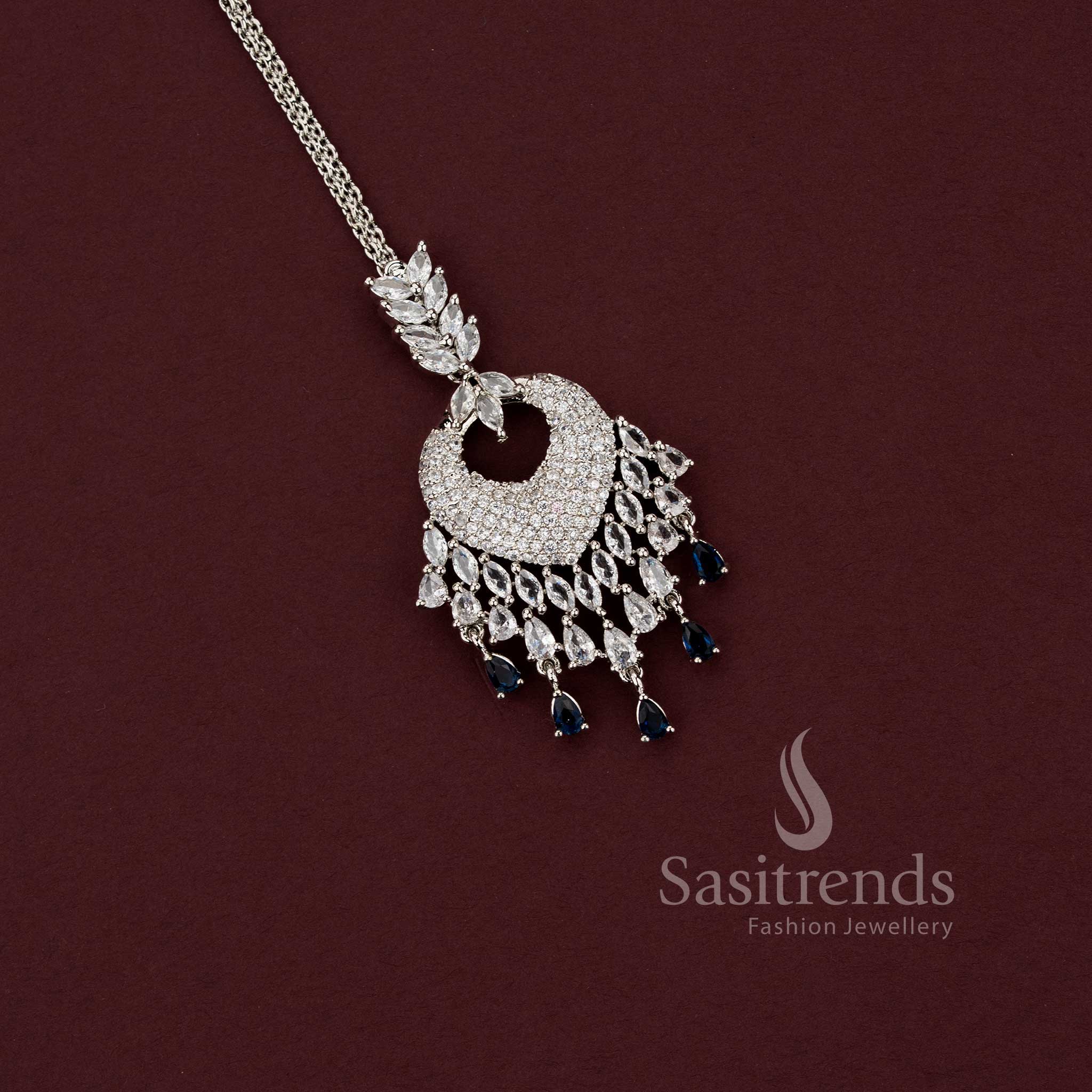 Elegant all-white American Diamond maang tikka with a spade-style motif and a wide fringe of clear teardrop stones, a versatile accessory for party wear sarees and formal events.