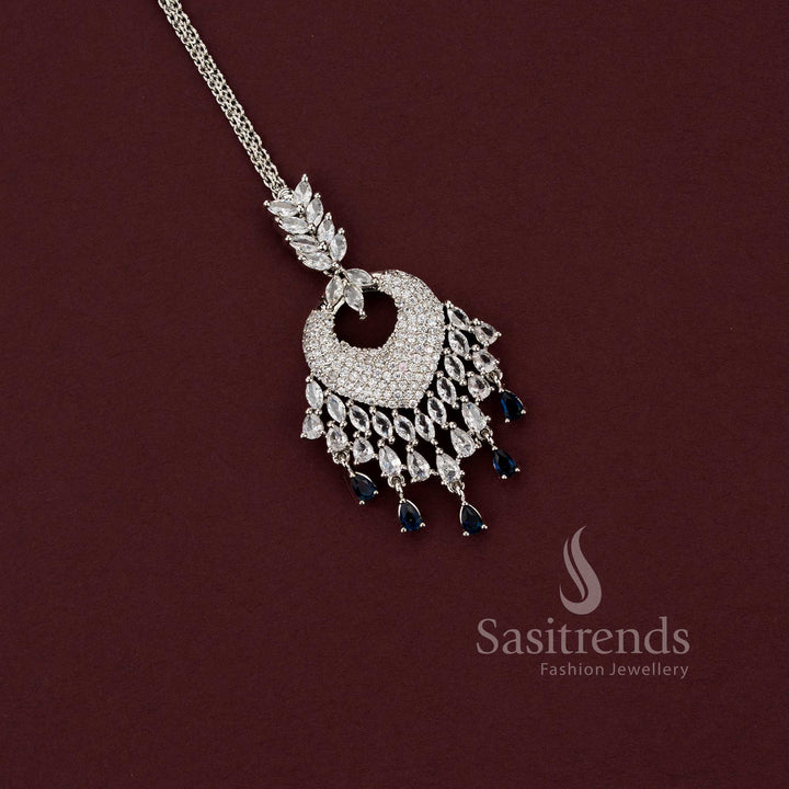 Elegant all-white American Diamond maang tikka with a spade-style motif and a wide fringe of clear teardrop stones, a versatile accessory for party wear sarees and formal events.