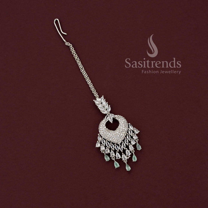 xquisite bridal rhodium silver maang tikka 2129F featuring a heart-shaped American Diamond pavé pendant with mint green stone drops, ideal for engagement lehengas and wedding functions