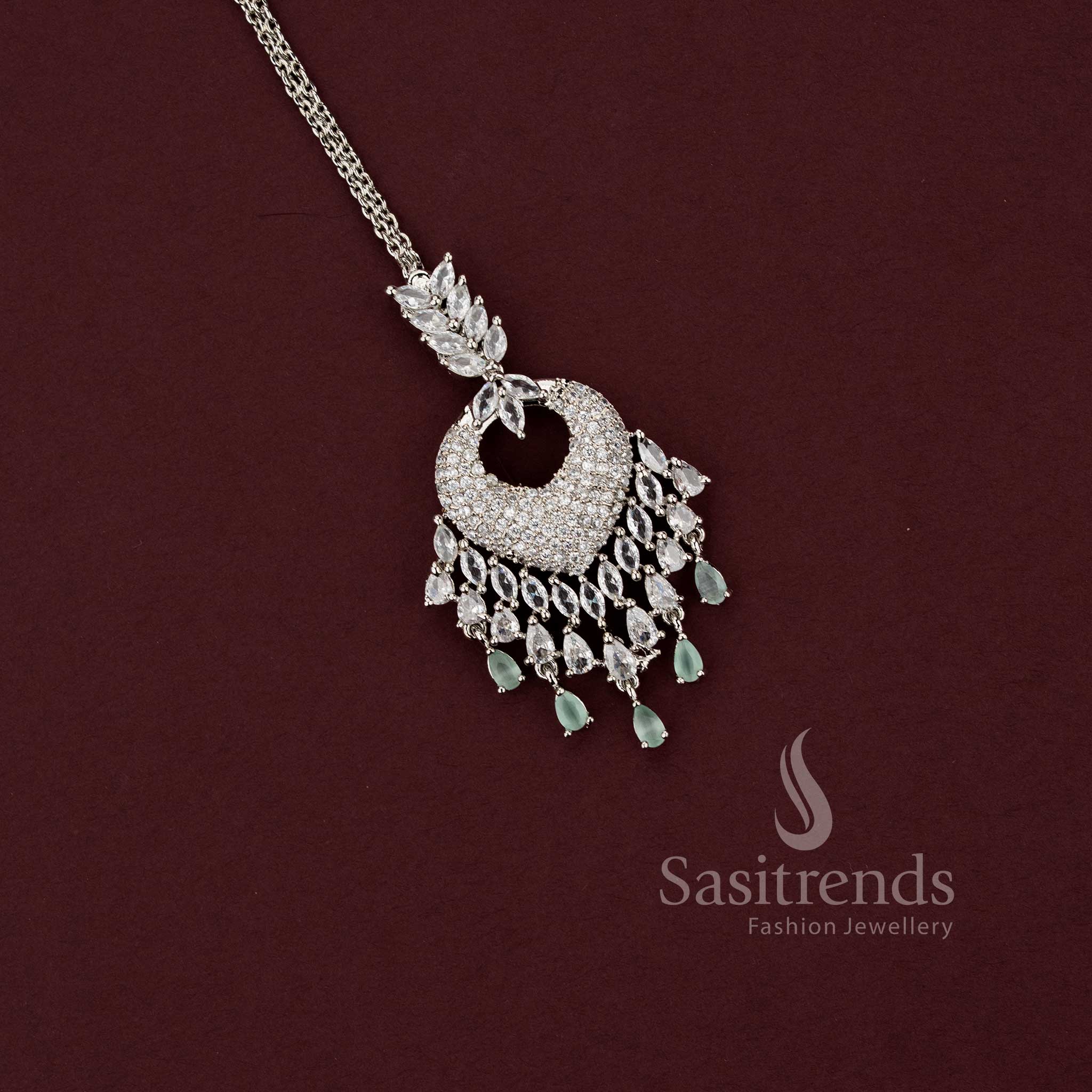 Elegant party wear silver AD stone maang tikka 2129F with a spade-style motif and a wide chandelier fringe of mint green teardrop beads, a perfect accessory for sarees and festive outfits.