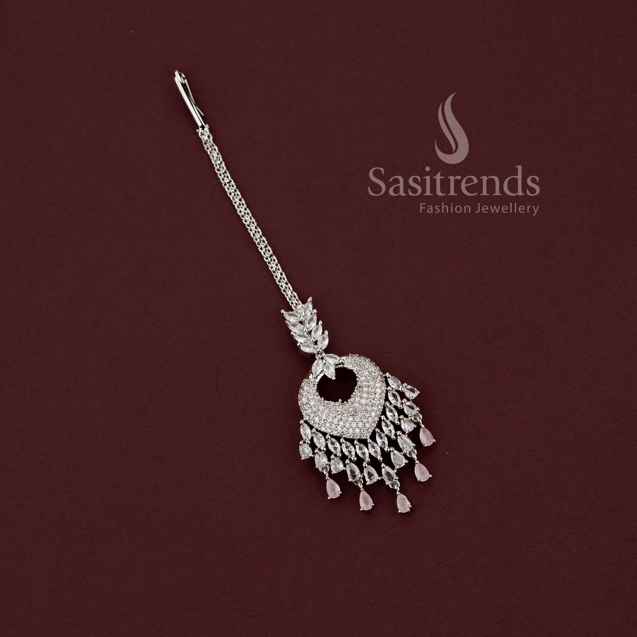 Romantic bridal rhodium silver maang tikka 2129F featuring a heart-shaped American Diamond pendant and delicate pink stone dangling drops, perfect for wedding lehengas and engagement ceremony look