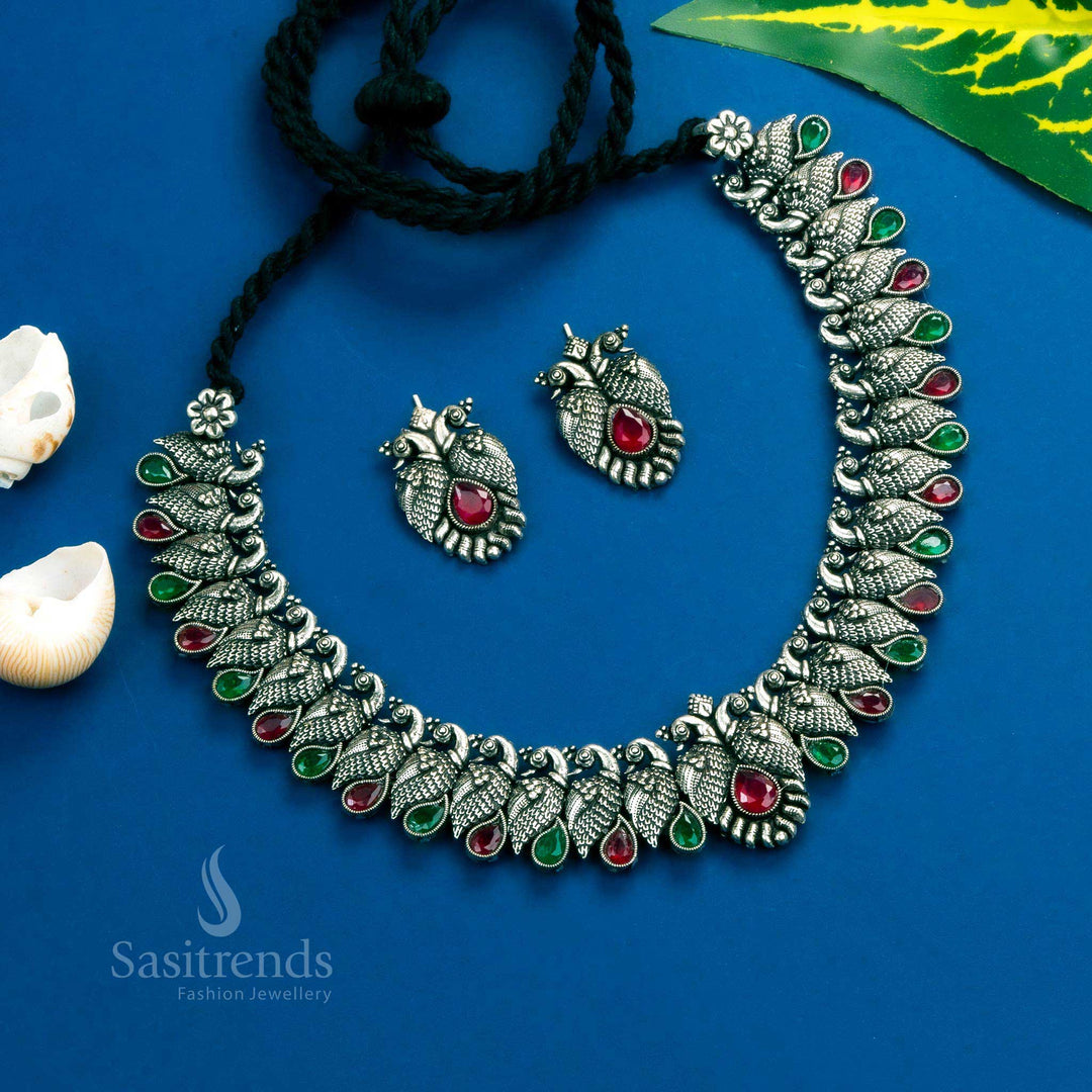 Elegant antique peacock Kushi necklace set in oxidised silver, designed with ruby-green tear drop stones - Sasitrends