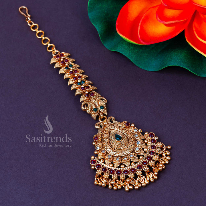 Temple-style matte gold maang tikka adorned with multicolour stones and intricate beaded drops, a grand bridal headpiece designed for vibrant ethnic festivals and timeless beauty – Sasitrends