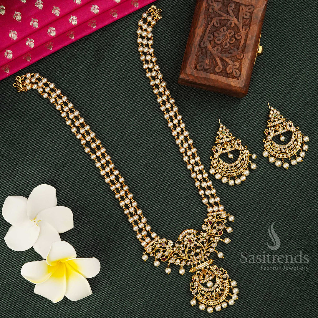 Temple-inspired long matte gold plated jewellery set featuring a majestic peacock pendant in bell-shaped artistry, adorned with elegant three-line pearls – a heritage statement piece ideal for saree occasions, weddings, and classical rituals – Sasitrends