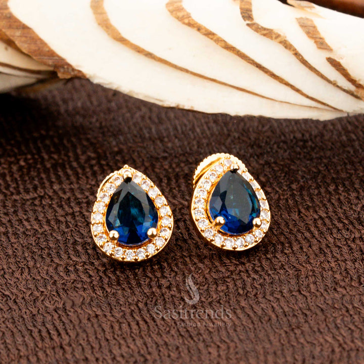Timeless gold-plated oval stud earrings showcasing striking blue American diamond stones, an exquisite bridal and festive wear accessory for sarees and special occasions - Sasitrends