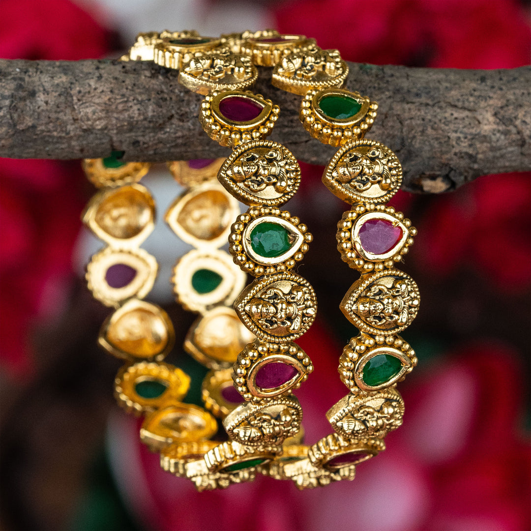 Ornate matte gold temple bangles featuring ruby-green kemp thilak style stones with Lakshmi icons, crafted for sacred bridal jewellery tradition and classic South Indian elegance – sasitrends