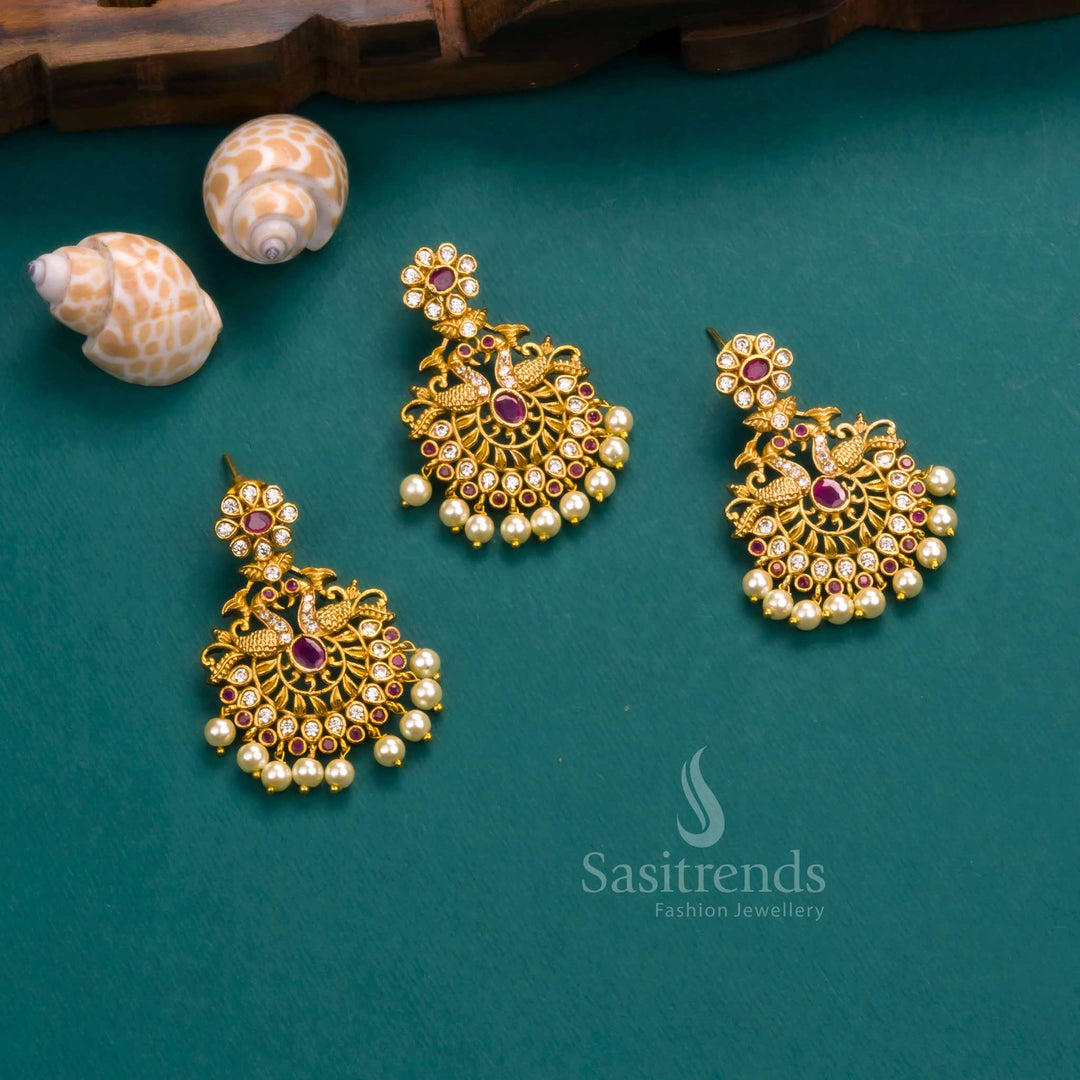 Premium temple matte gold plated peacock pendant jewellery set featuring white and ruby AD stones with classic pearl drops and matching earrings – a regal festive choice from Sasitrends