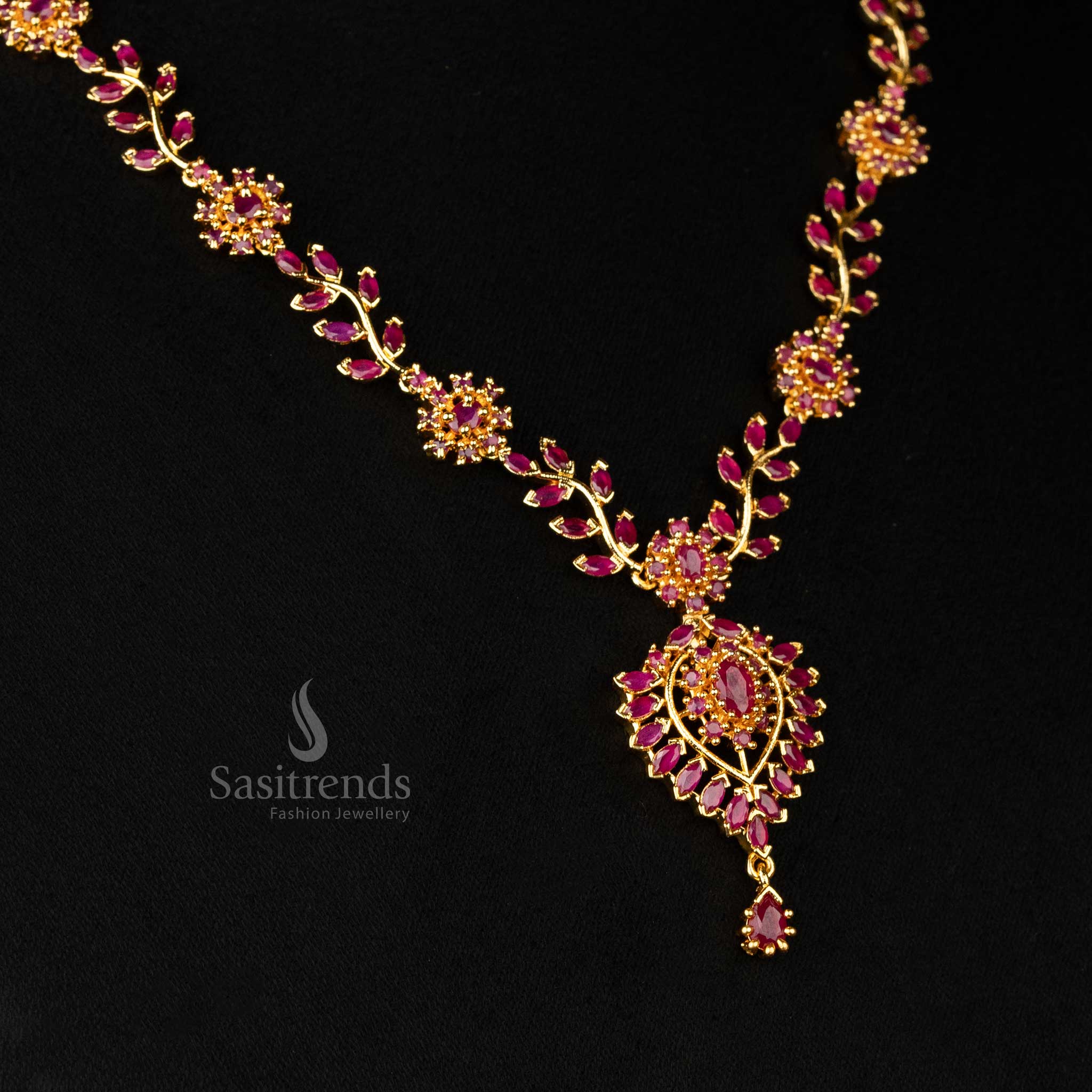 Detailed view of ruby accents on the micro gold-plated floral motif pendant - Sasitrends