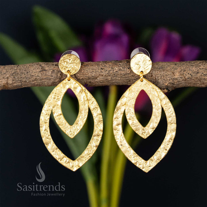 Double teardrop design gold-plated earrings against a floral backdrop