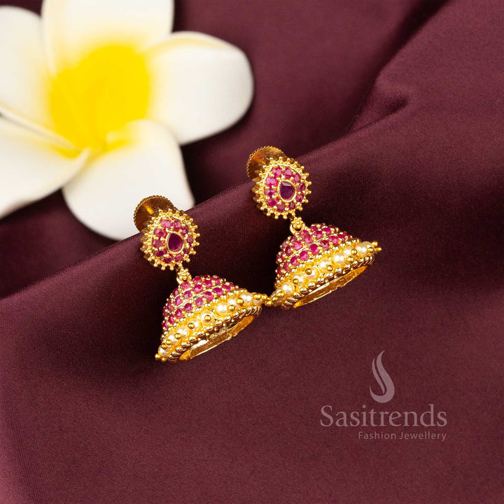 Radiant ruby micro gold finished AD stone jhumka earrings adorned with lustrous pearl chains and temple-inspired etched pattern – Sasitrends