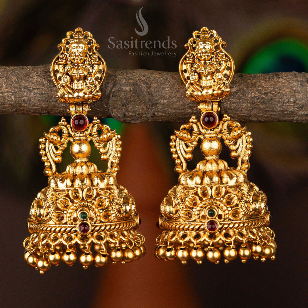 Traditional matte gold jhumkas adorned with antique ruby-green  stones, Lakshmi figurework and classic South Indian drum-style drop design, perfect for ethnic bridal wear – Sasitrends