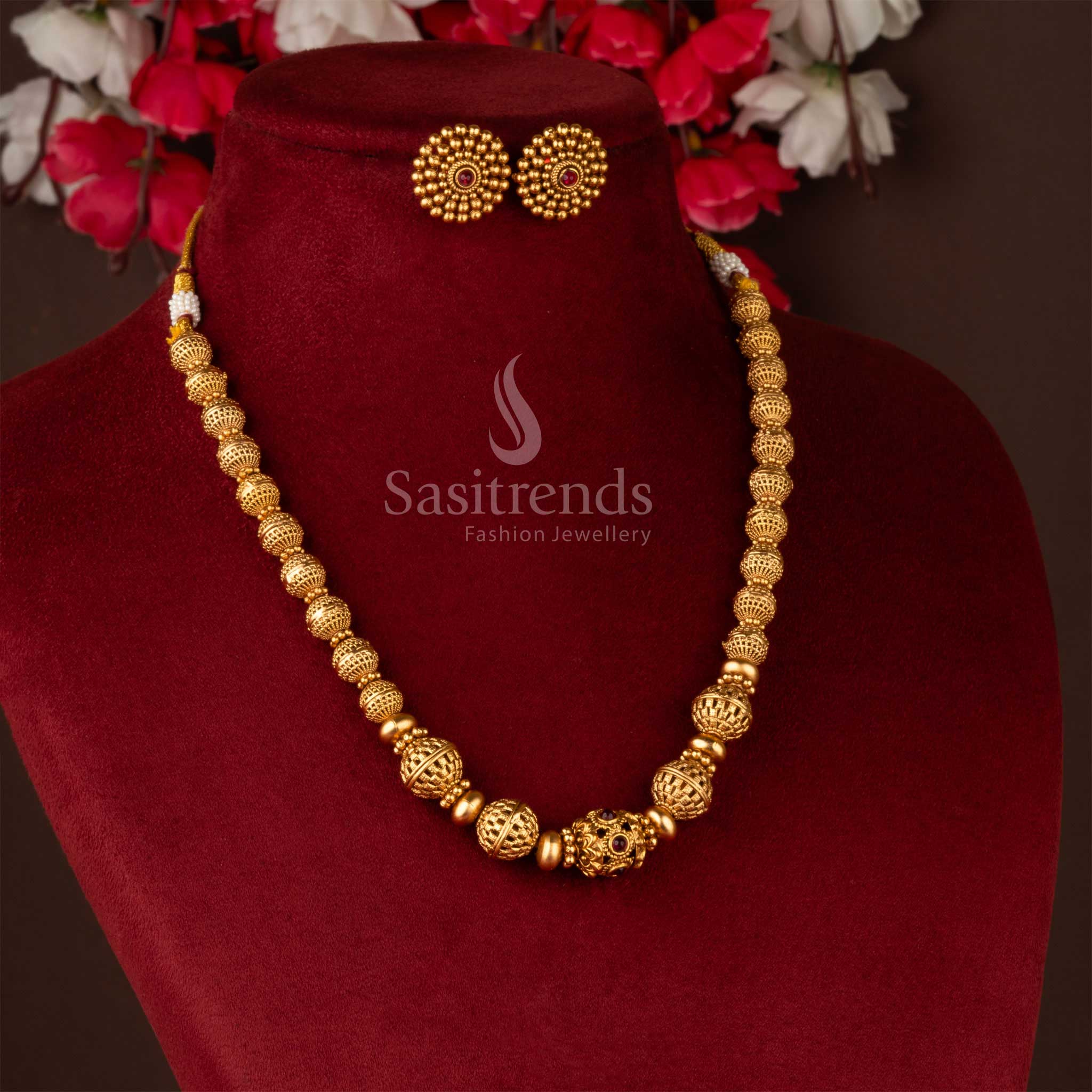 Traditional gold-plated beaded brass necklace and earrings on burgundy display - Sasitrends