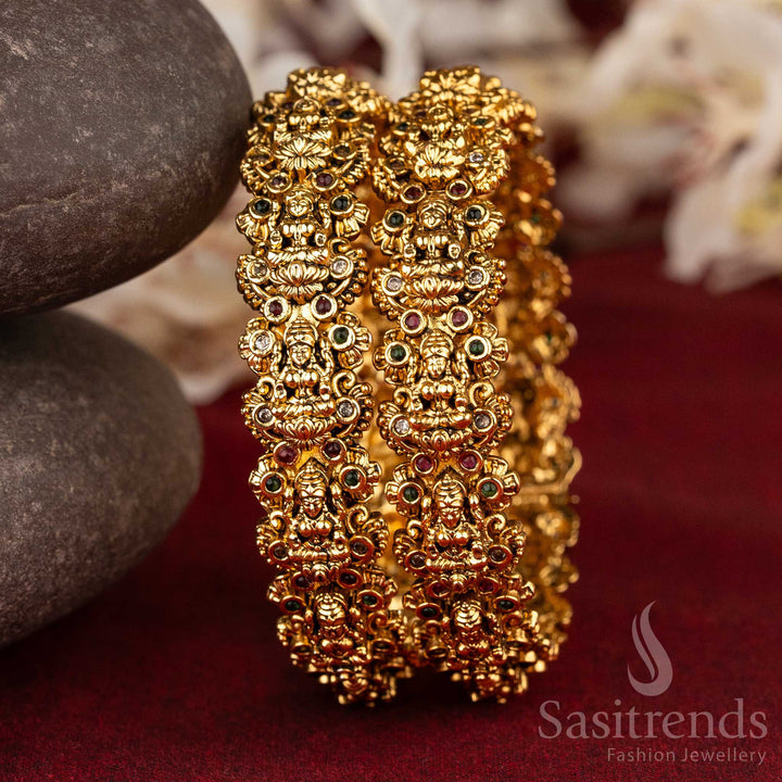 Temple-style bridal bangles in matte gold finish featuring divine Lakshmi engravings and multi-colour AD stone embellishments – a radiant piece of ethnic charm and sacred bridal jewellery by Sasitrends