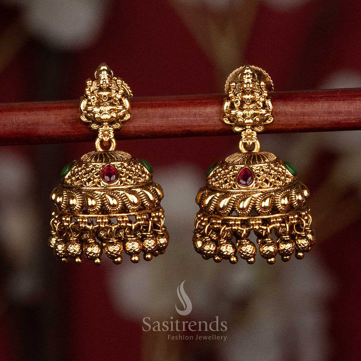 Traditional temple style matte gold ruby green AD stone Lakshmi Devi jhumka earrings with sculpted stud motif and rich layered bead detailing, high quality jewellery for saree wear- Sasitrends