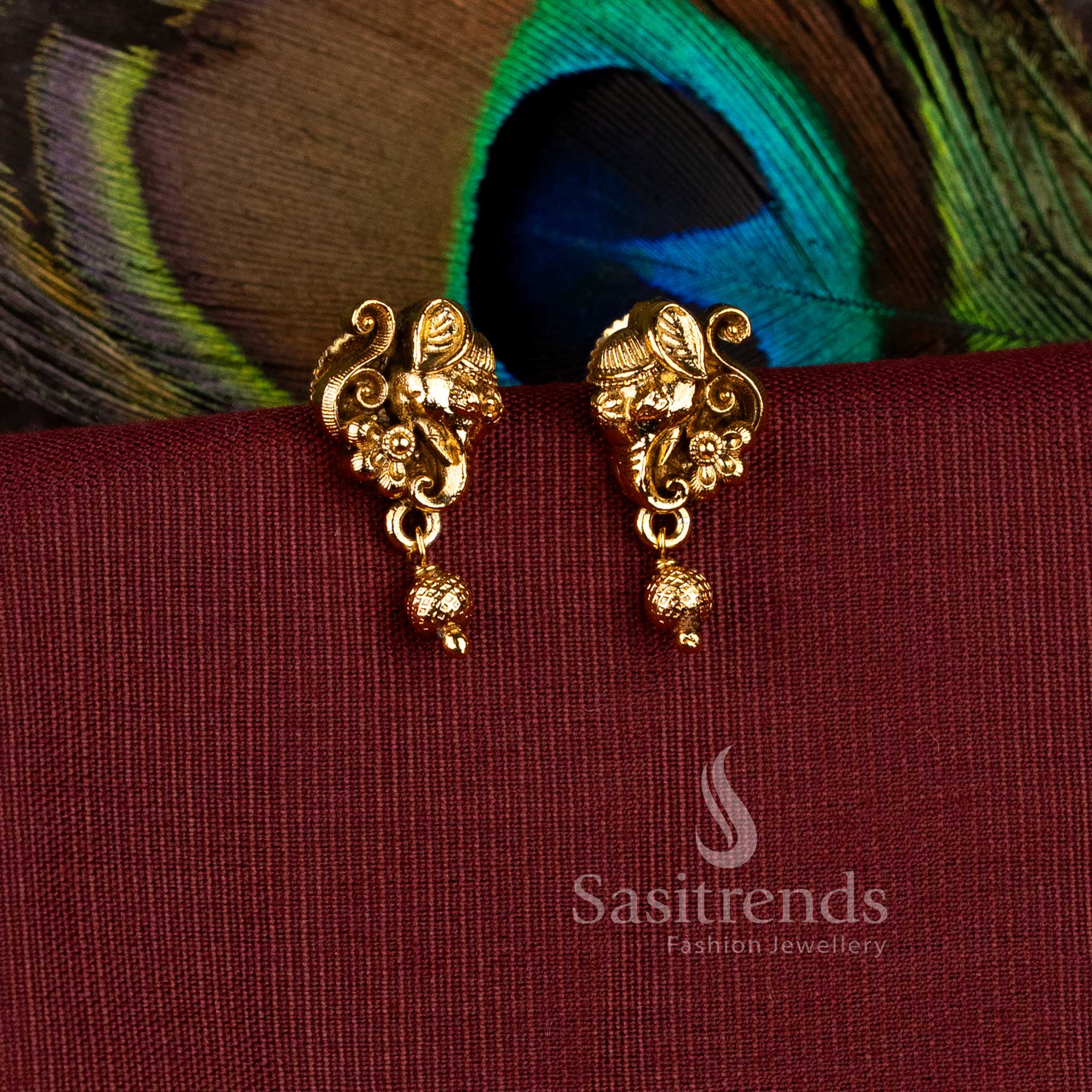 Traditional matte gold plated Lord Ganesha temple stud earrings with hanging textured gold ball droplets by Sasitrends.