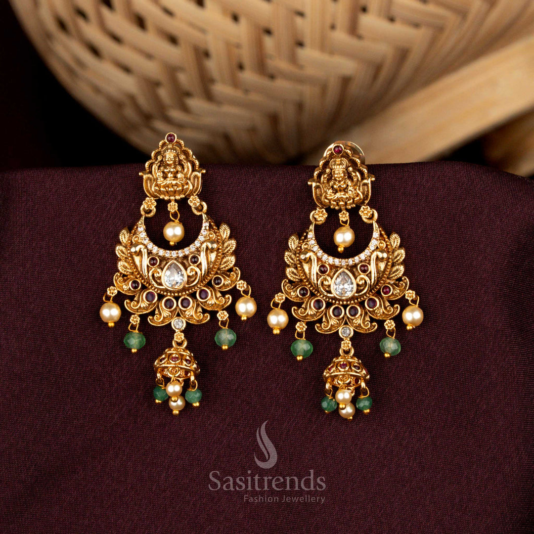 Eternal white ruby Lakshmi temple crescent earrings featuring divine floral carvings, opulent matte gold brilliance, AD embellishments, and splendid jhumka artistry – Sasitrends