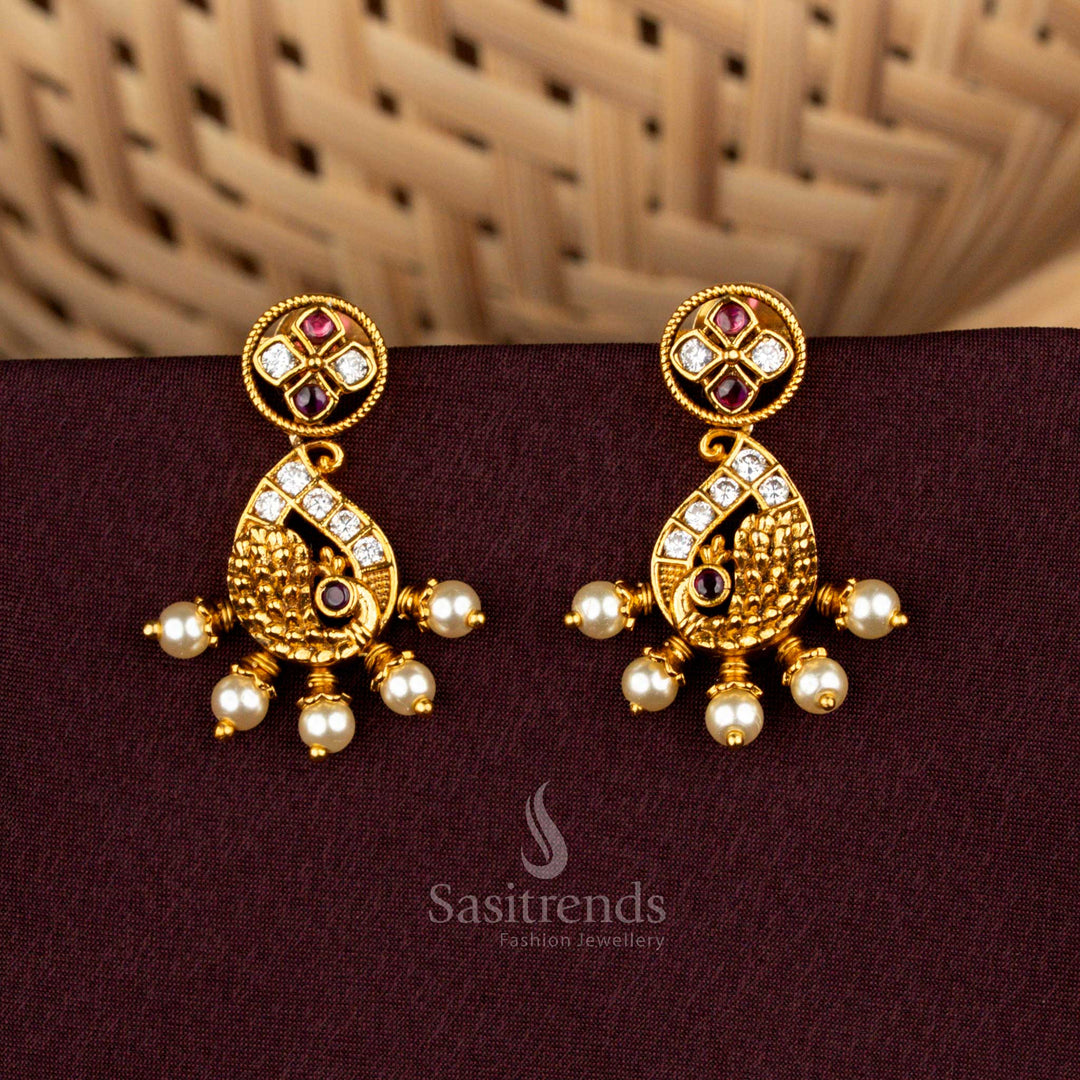 Splendid white ruby stud earrings featuring paisley peacock artistry, radiant matte gold detailing, aristocratic AD brilliance, and divine pearl drops for bridal grandeur – Sasitrends